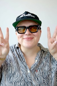 a woman wearing sunglasses and a zebra print shirt making a peace sign